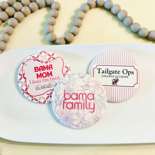 3 round Alabama buttons with text on a white tray with a gray beaded garland