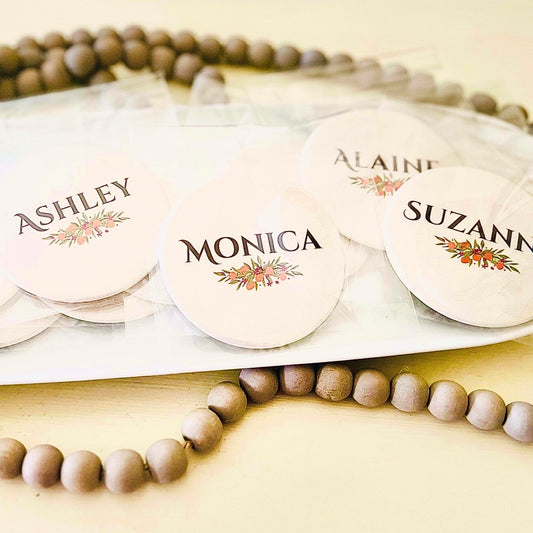 Round name tags with personalized names on a wooden beaded tray.