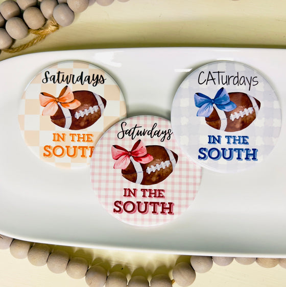 Three round buttons with football and bow designs and text on a white tray