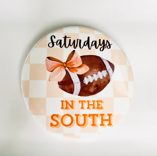 Round button with football, orange bow, and text 'Saturdays in the South' on an orange checkered background.