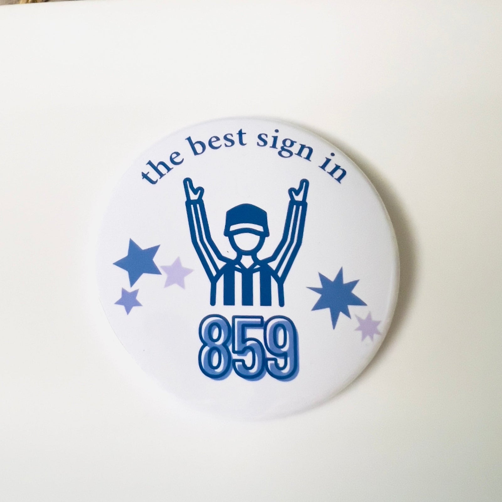 Circular button with a referee graphic and text 'the best sign in 859' on a white background.