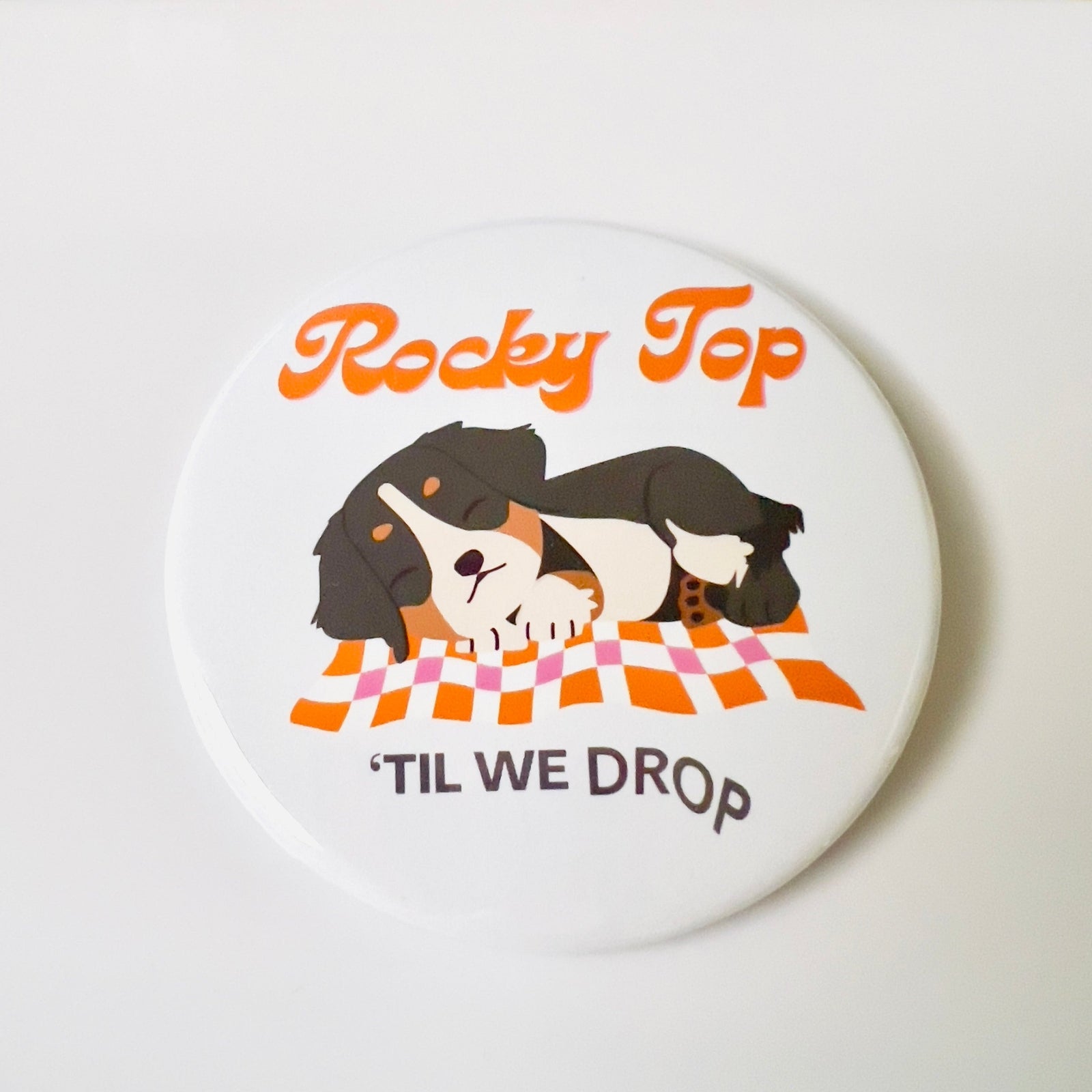 Round button with cartoon dog illustration and text 'Rocky Top TIL WE DROP' on a white background