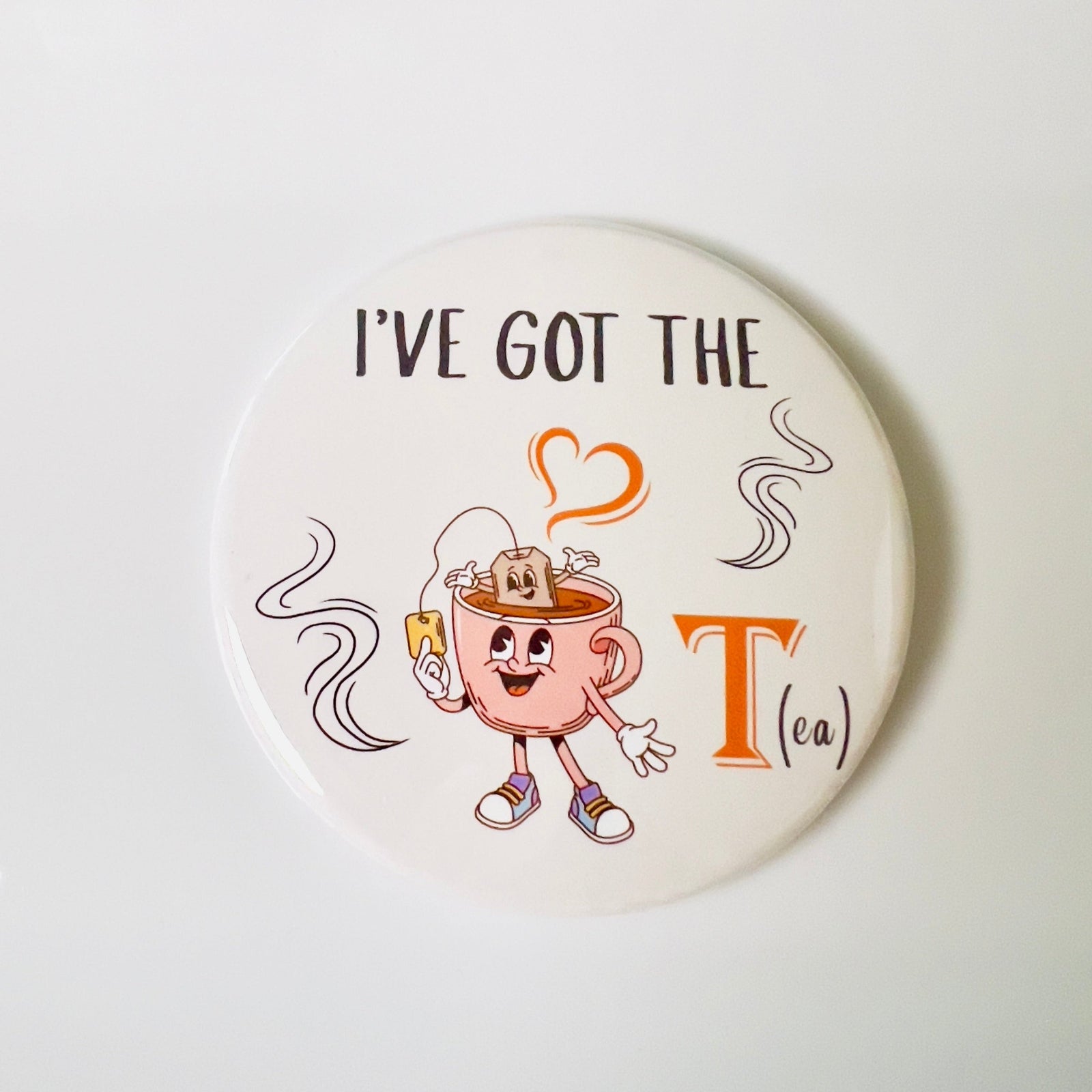 Round button with cartoon teacup character and text 'I've Got the Tea' on a white background