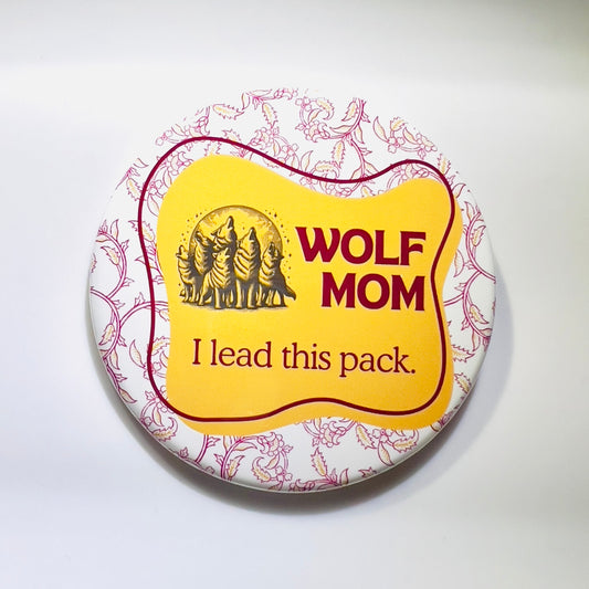 Button badge with 'Wolf Mom' text and wolf pack illustration on a floral background