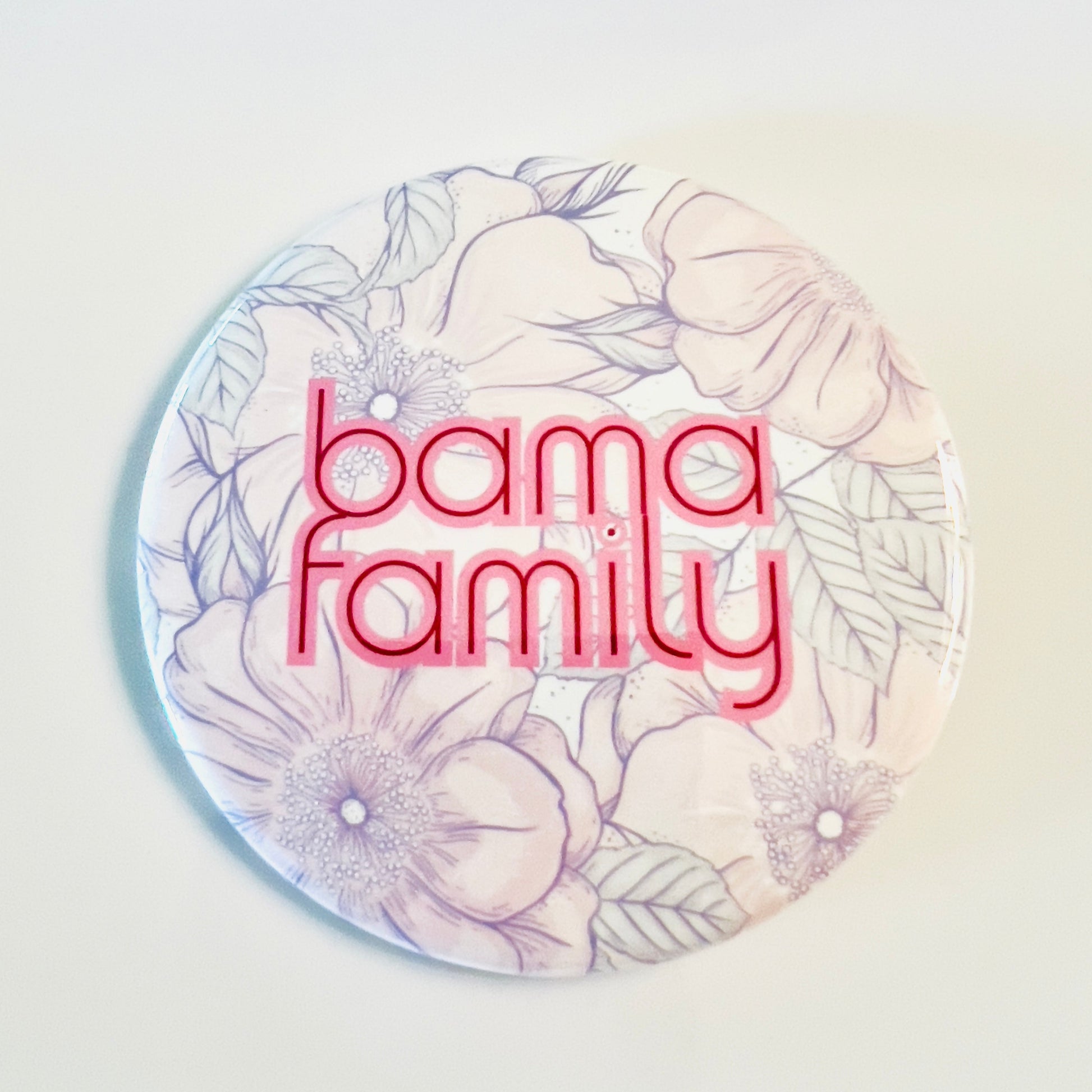 Round button with 'bama family' text and floral design on a gradient background