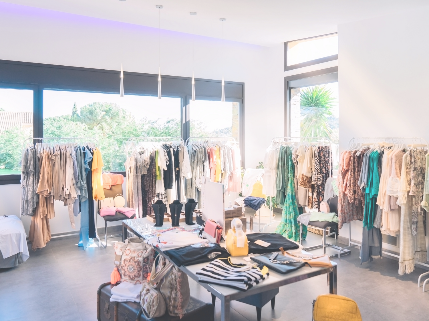 Bright modern boutique with racks of clothes and a display table.