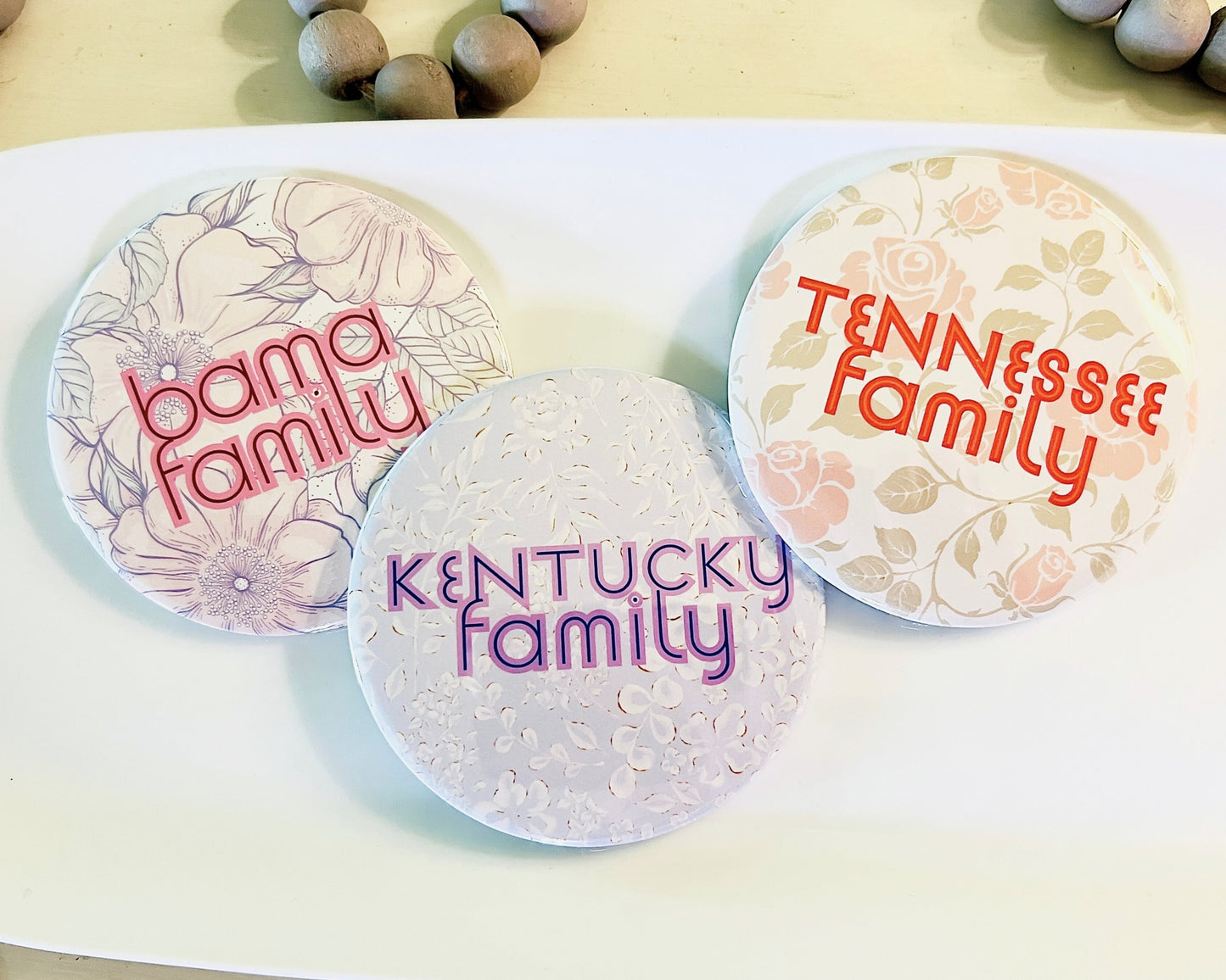 Three round buttons with 'bama family', 'TENNESSEE family', and 'Kentucky family' text on a white surface